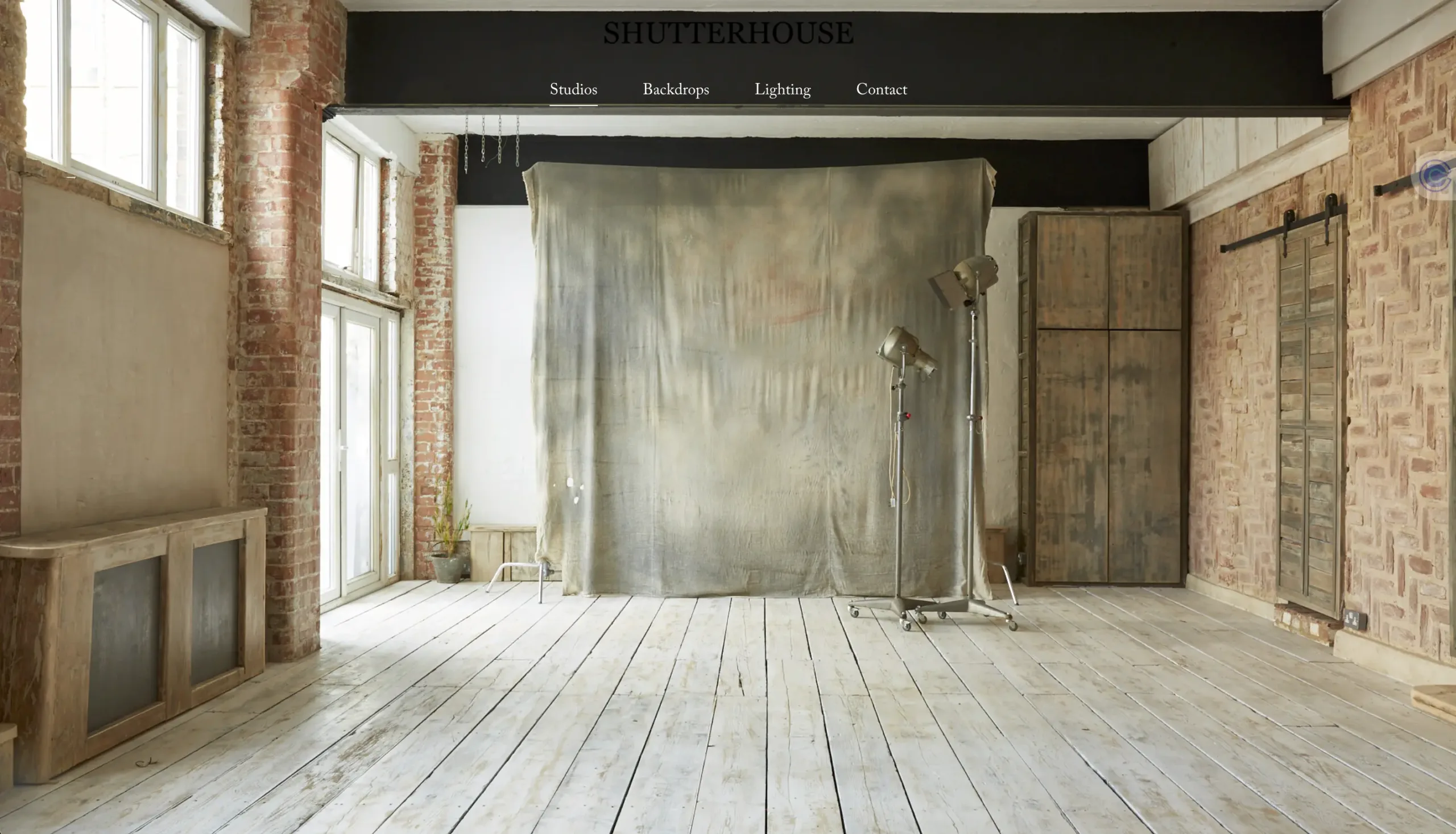 Shutter House studio website still. Rustic photo and video studio with wooden flooring and red brick walls.